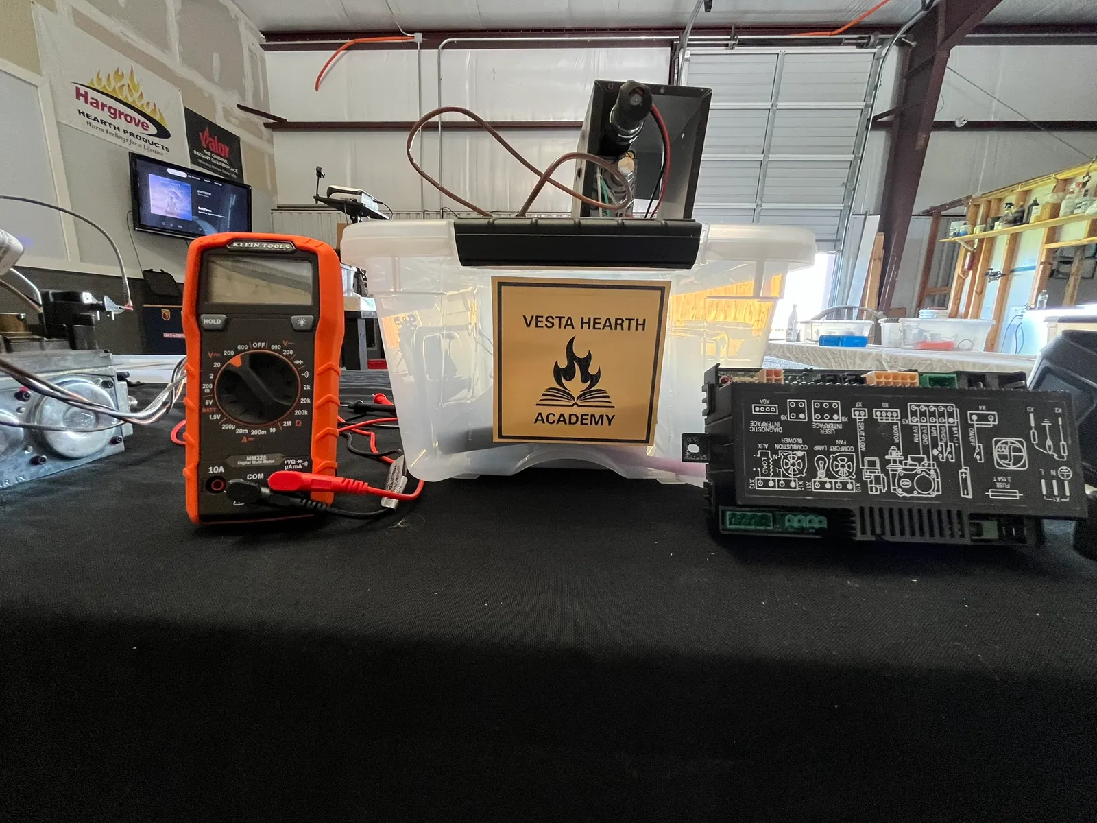A Vesta Hearth Academy training bench with a multimeter, a gas valve, and a fireplace control board
